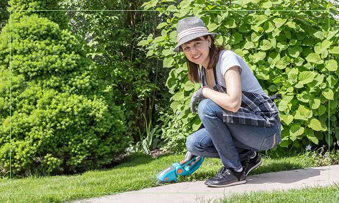 A girl kneeling down on the ground with her skateboard.